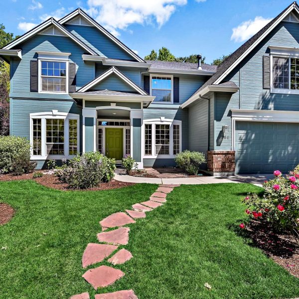 Elegant two-story home in Harris Ranch, Boise, featuring a landscaped front yard, stone pathway, and charming blue exterior with a welcoming front entry.